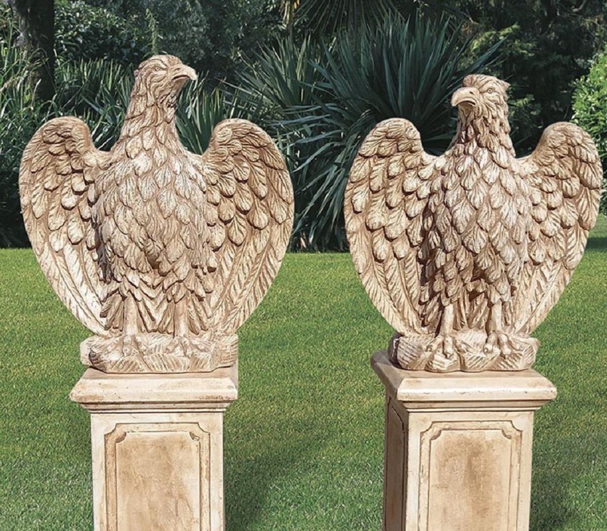 You see two eagle figures, each standing on a pillar. The sculptures are located in a well-kept garden.