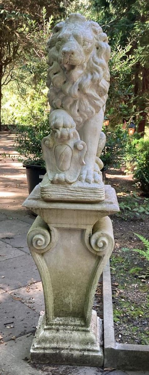 Vous voyez une statue de lion royal debout sur un piédestal dans un jardin.