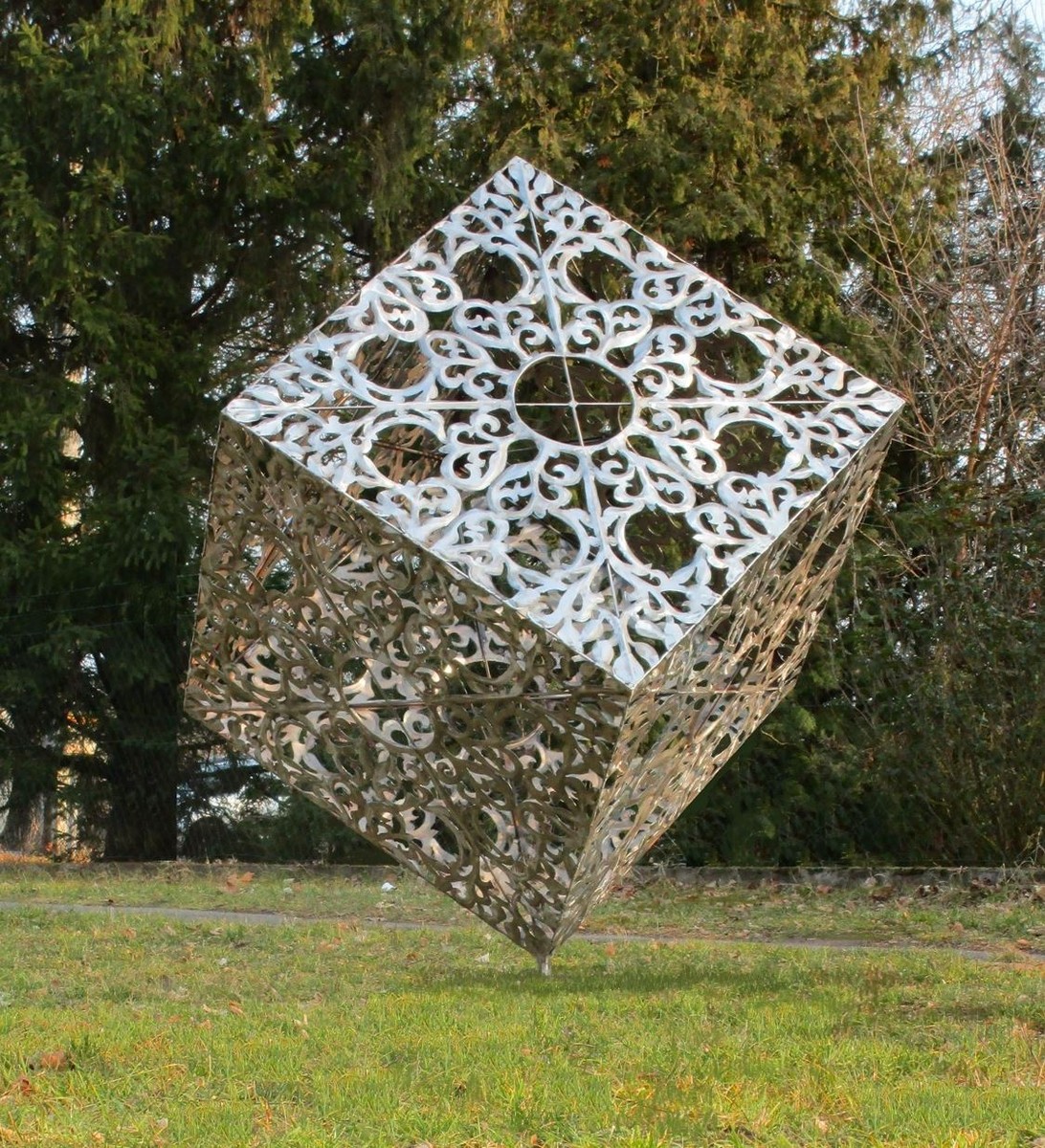 Vous voyez un énorme cube en acier inoxydable dans un jardin.