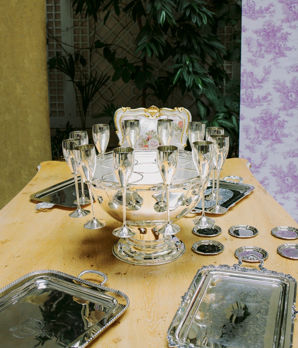 The new accessory collection by Harald Glööckler Pompöös Provence by Casa Padrino. You see silver trays, coasters, champagne glasses, champagne coolers on a table in country house style