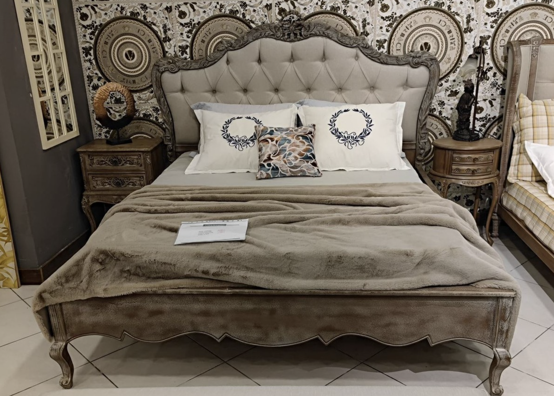 Una lujosa cama doble de color gris antiguo con reposacabezas acolchado y detalles reales, que crean una atmósfera majestuosa y elegante en el dormitorio.