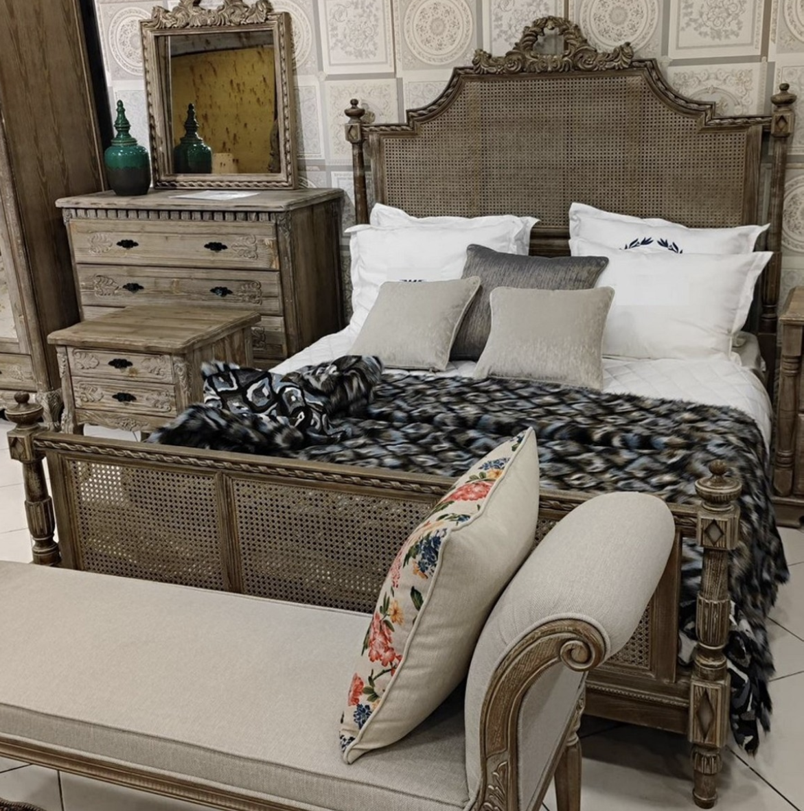 You see a luxurious solid double bed on feet with very beautiful rattan weave from the Harald Glööckler Pompöös Provence collection 2024 in a baroque country house style in the colors brown gray made of solid wood.