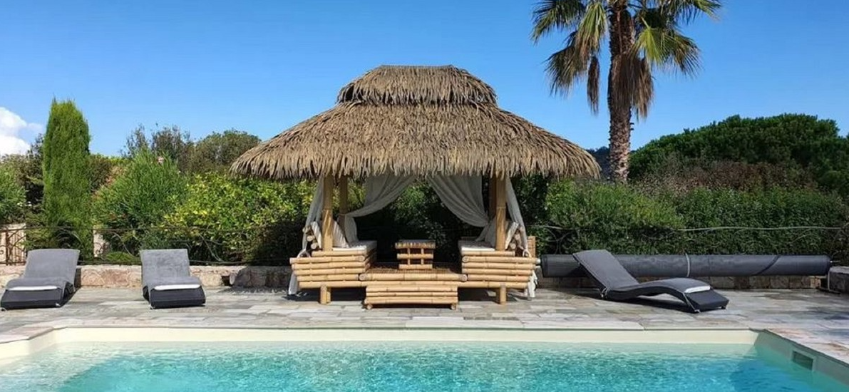 Luxueux pool house en bambou avec toit de chaume et chaises longues