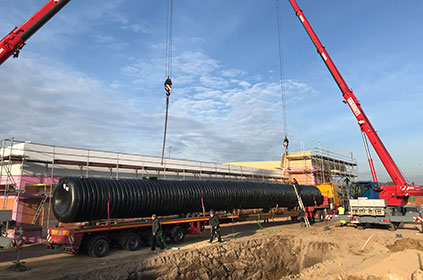 Einlass des Löschwassertanks per Kran in Baugrube.